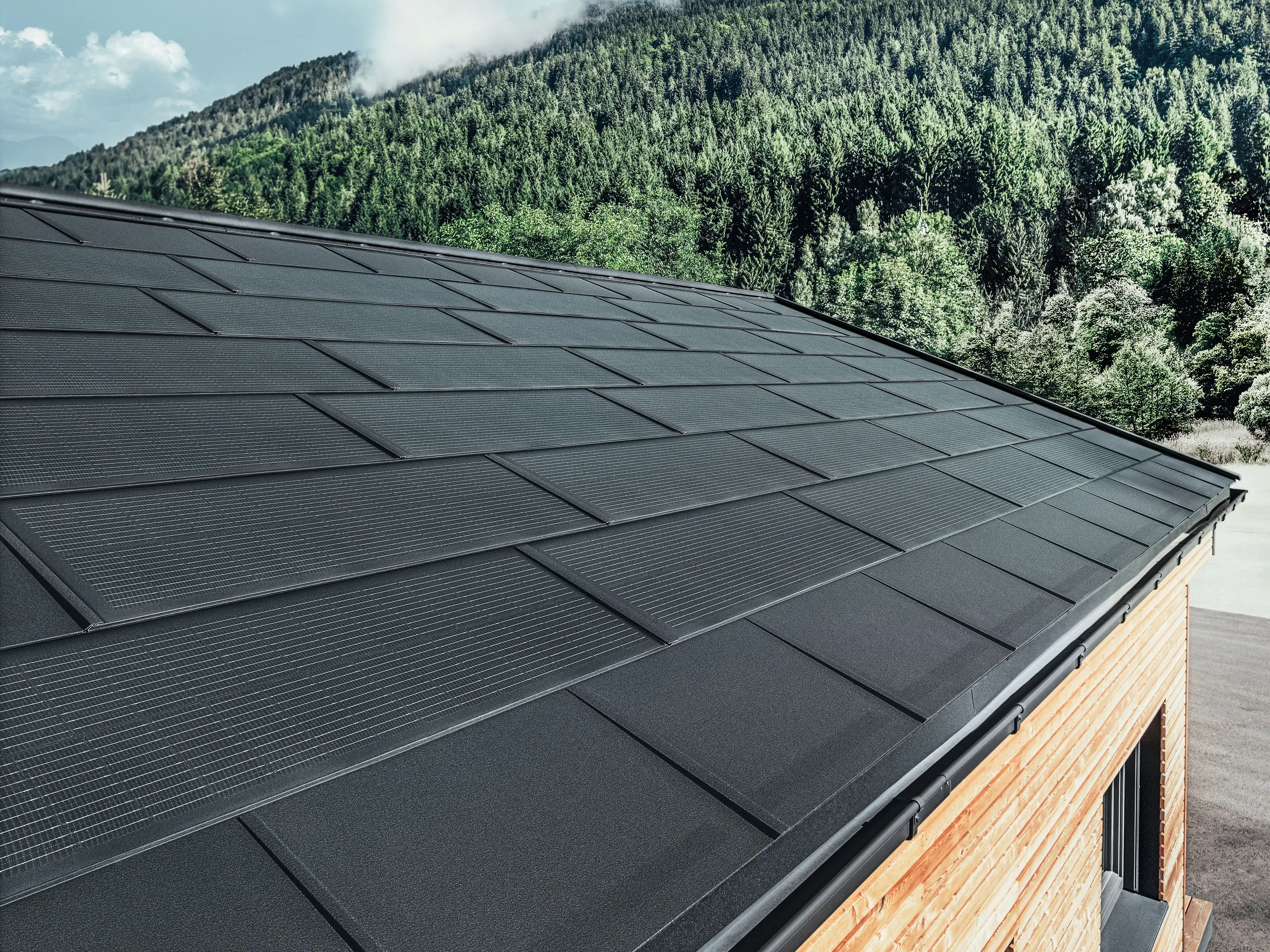 PREFA Solardachplatte in großer Ausführung kombiniert mit der Dachplatte R.16 in Schwarz, Kastenrinne und Lärchenholz-Fassade