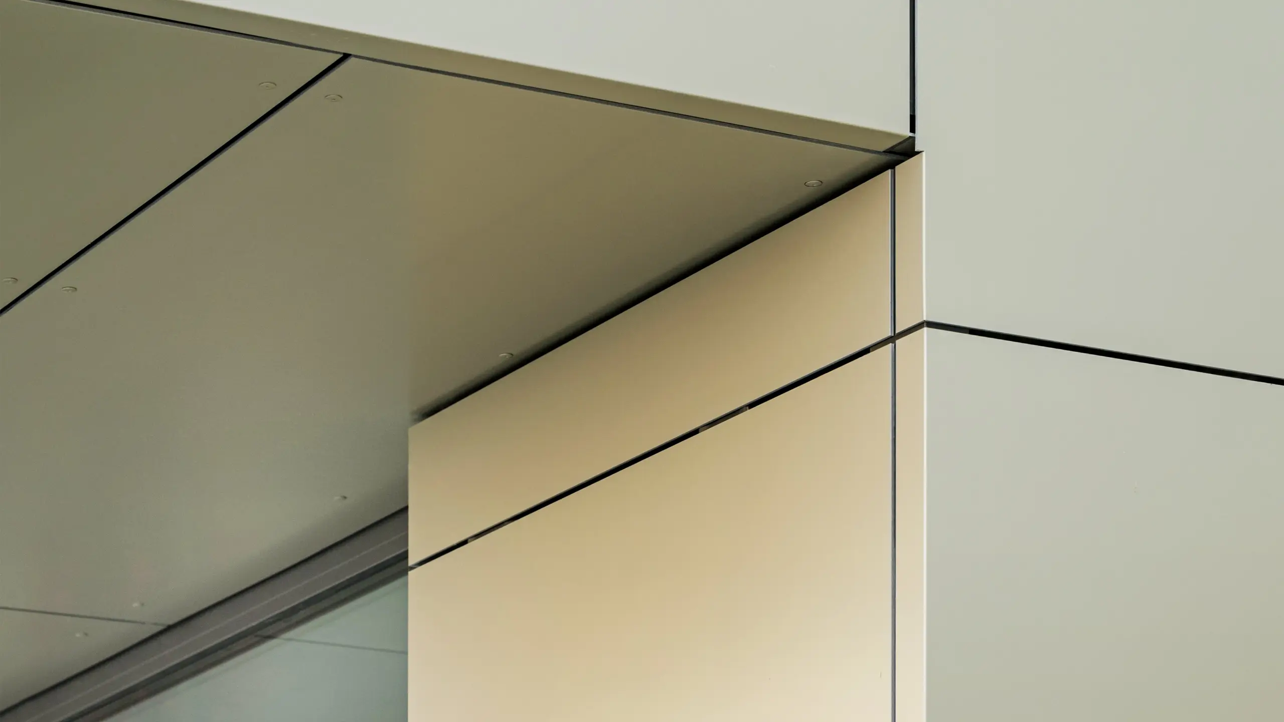 Detaljni prikaz fasade gradske vijećnice u Alzenauu, koji prikazuje precizne rubove i prijelaze PREFA aluminijskih kompozitnih ploča u brončanoj boji. Ploče su savršeno spojene, stvarajući jasne, moderne linije. Metalik sjaj ploča naglašavaju fini spojevi i minimalistički detalji arhitekture, što fasadi daje elegantan i suvremen izgled.