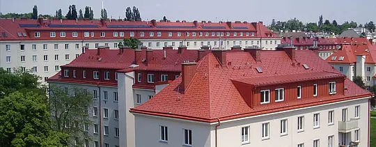 Snimka stambenih zgrada kompleksa Hugo Breitner Hof u Beču. Krovovi su pokriveni PREFA krovnom šindrom u ciglasto crvenoj.