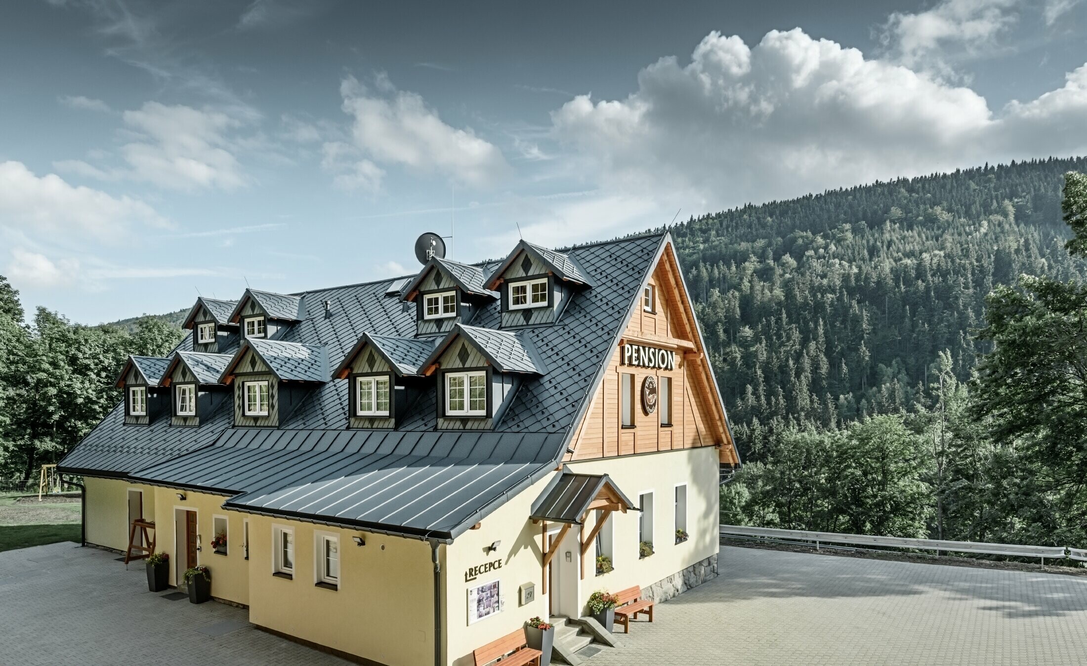 Pansion u Češkoj pokriven strmim krovom i velikim brojem krovnih kućica s aluminijskim krovom PREFA, ljuskastim krovom od rombova sa zaštitom od snijega