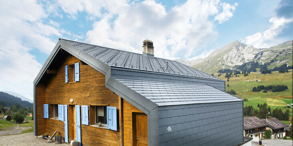 Kuća u planini u Švicarskoj s drvenom fasadom u kombinaciji s PREFA krovnim i zidnim rombom u kameno sivoj boji
