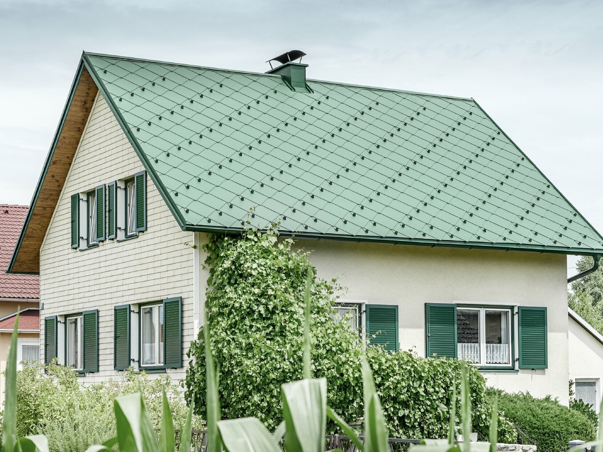 Klasična jednoobiteljska kuća s dvostrešnim krovom s krovnim pokrovom od aluminija u mahovinasto zelenoj boji sa zelenim prozorskim kapcima