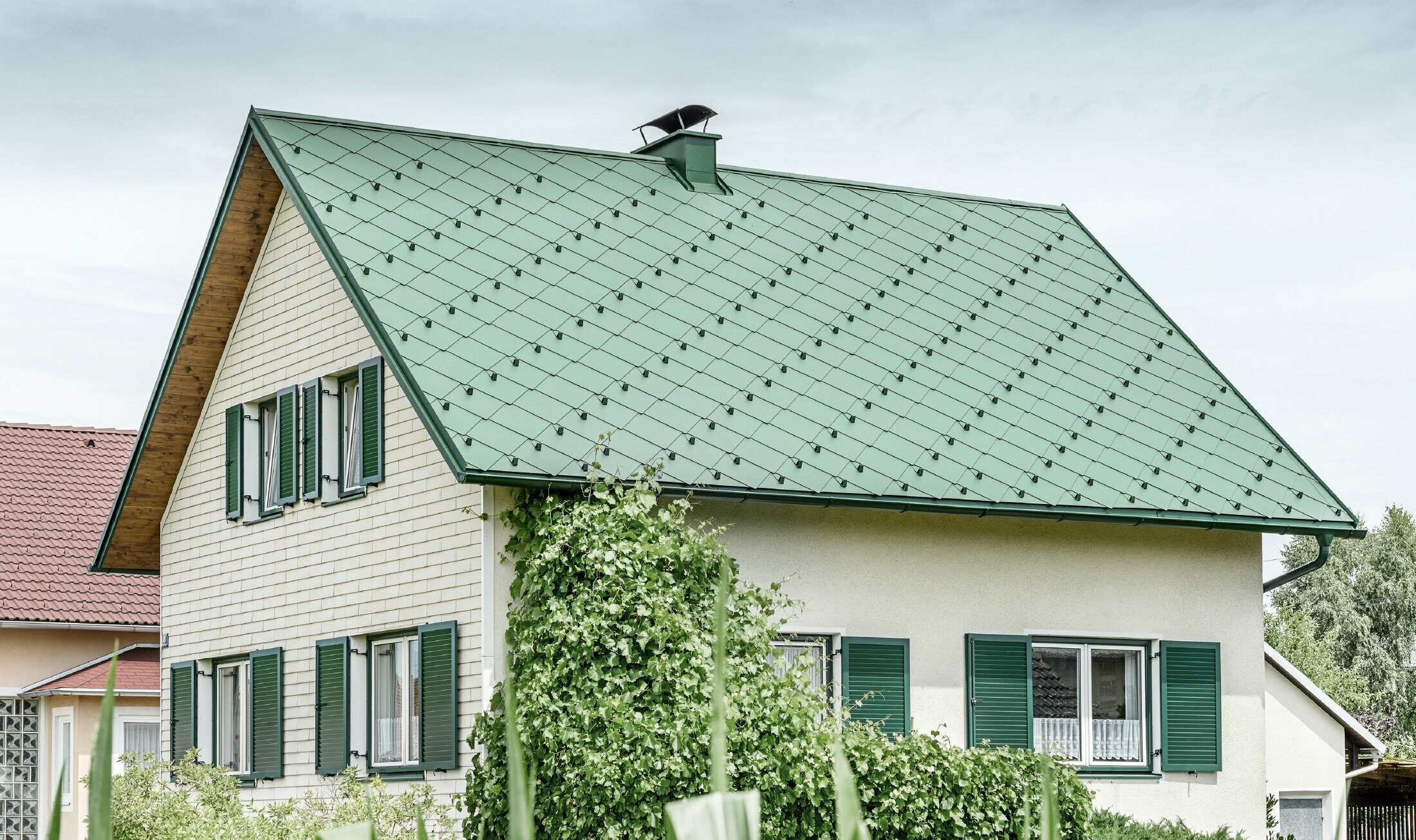 Klasična jednoobiteljska kuća s dvostrešnim krovom s krovnim pokrovom od aluminija u mahovinasto zelenoj boji sa zelenim prozorskim kapcima