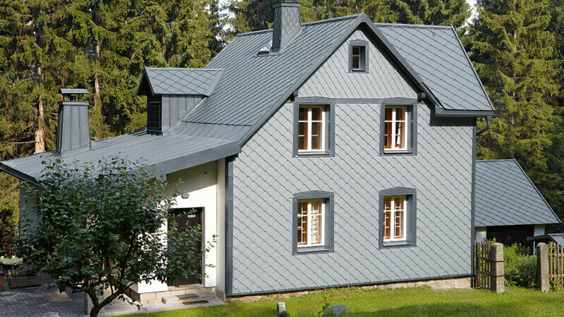 Obiteljska kuća u šumskom okruženju s PREFA aluminijskom fasadom otpornom na vremenske utjecaje u svijetlo sivoj boji.