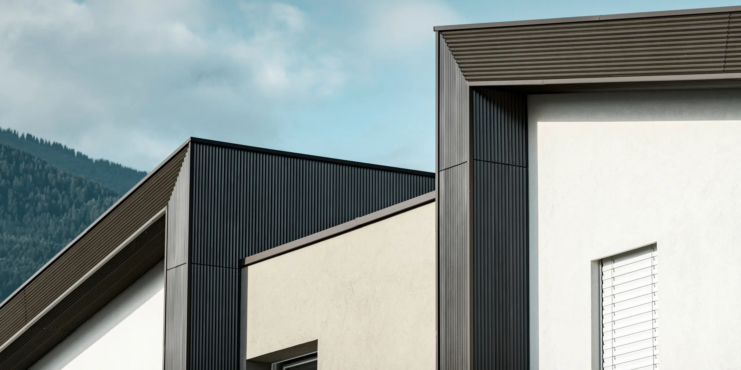 Die Fassade der Wohnhausanlage Les Dailles wurde großflächig mit dem eindrucksvollen PREFA Zackenprofil in Bronze verkleidet. Das Dach des Gebäudes wurde mit PREFALZ in Bronze eingedeckt.