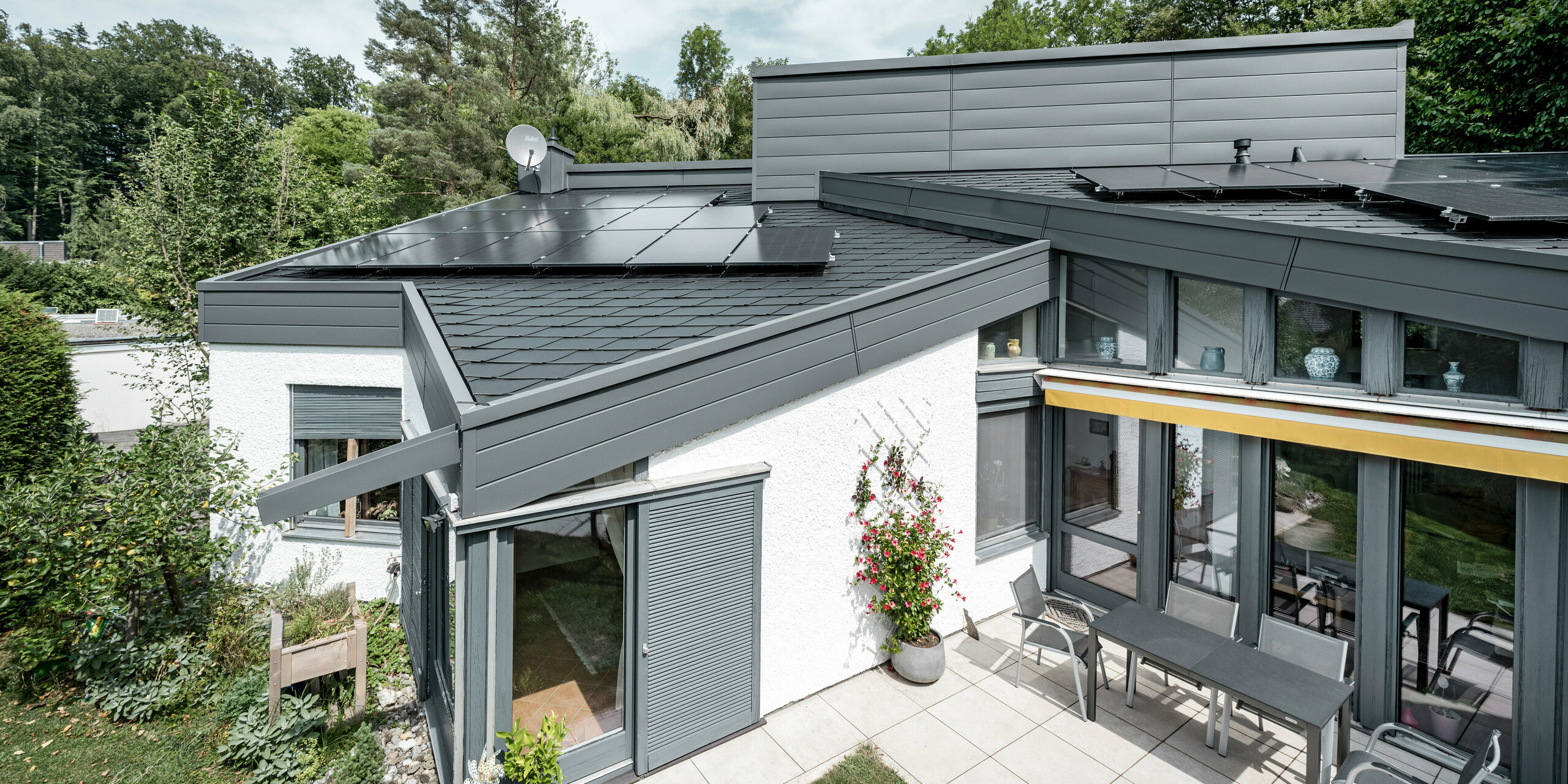 Ein Einfamilienhaus, das mit PREFA Dachschindeln DS.19 in schwarz eingedeckt wurde. Für Teile der Fassade wurden PREFA Sidings in P.10 dunkelgrau verwendet. 