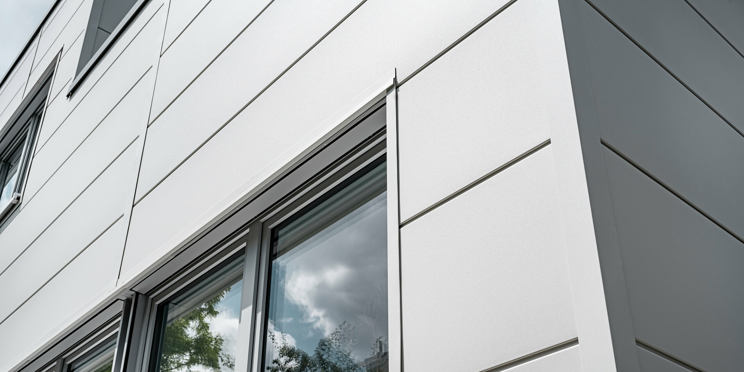 Großformatige PREFA Sidings umhüllen ein Firmengebäude in Oberschleißheim (Deutschland). Die extrabreiten Fassadenelemente aus Aluminium sind in der Farbe Prefaweiß gehalten.