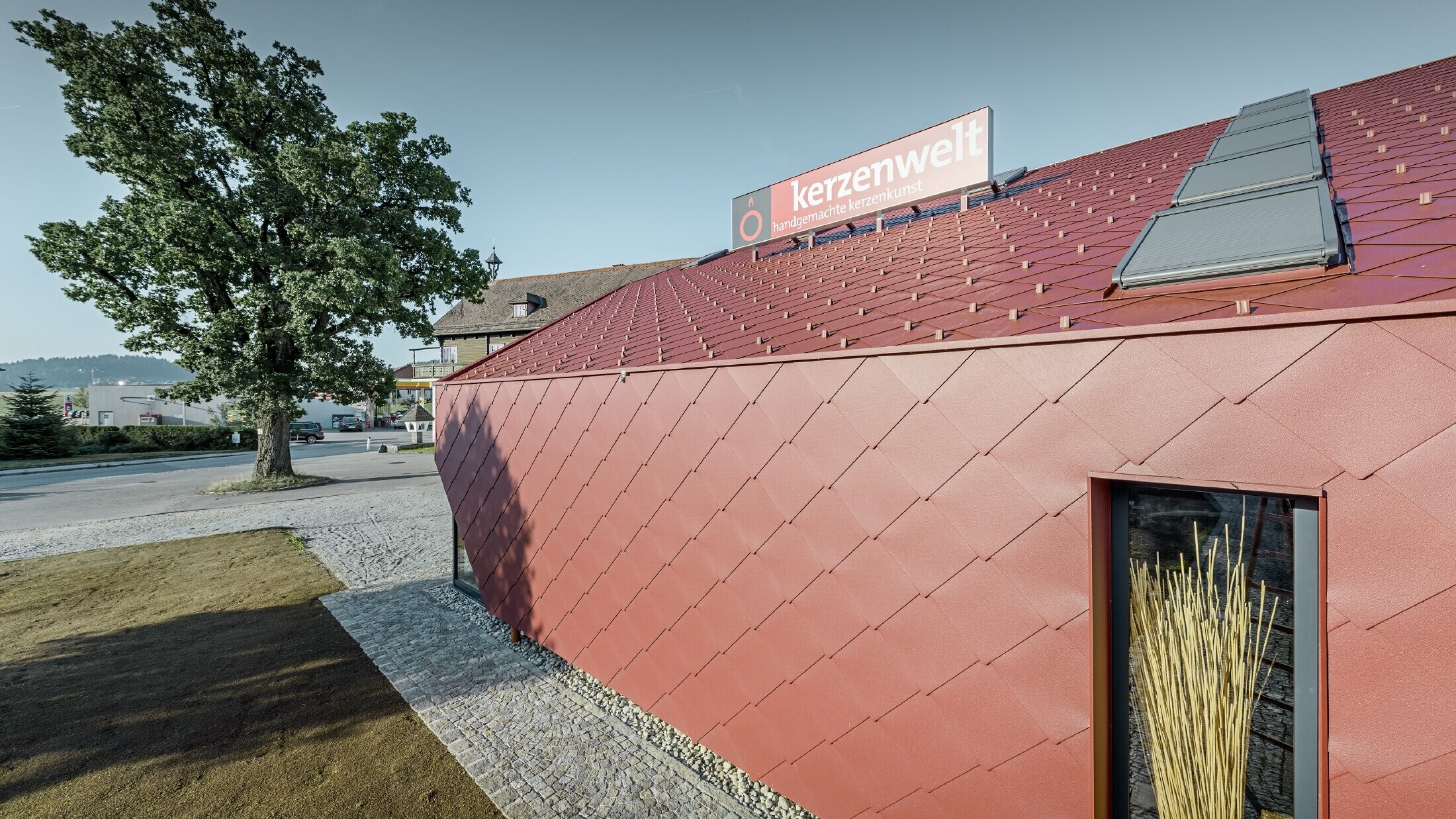 Svjećarna Kerzenwelt u Schläglu u cijelosti je nanovo pokrivena PREFA rombom. Krovni pokrivač i fasadna obloga izvedeni su s rombom 44 × 44 u oksid crvenoj.