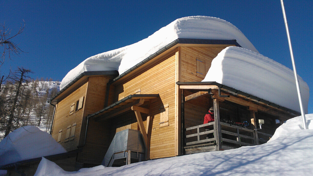 Koliba Capanna Buffalora s više centimetara snijega na krovu. 