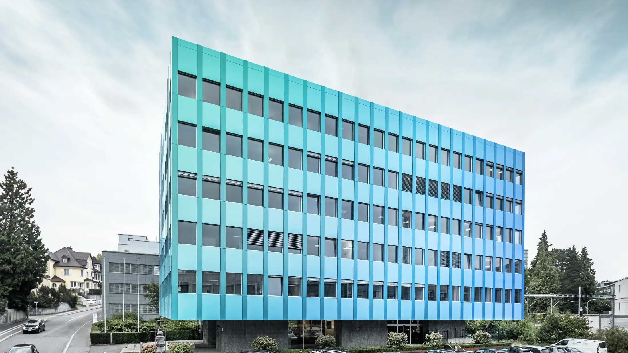 Bočni pogled na Wielandhaus u Aarauu; pročelje je obloženo kompozitnim pločama PREFABOND od aluminija tvrtke PREFA, koji blistaju u plavo-zelenoj boji zahvaljujući posebnom postupku oblaganja.