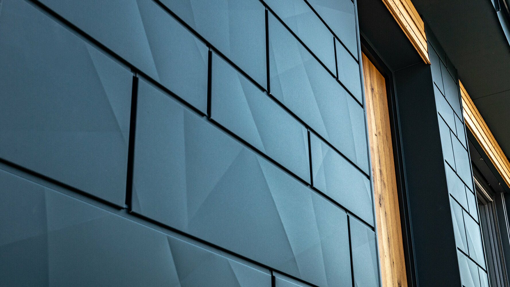 PREFA fasadni paneli s efektom prelamanja; PREFA aluminijski panel Siding.X u antracit boji kombiniran s drvenom fasadom.