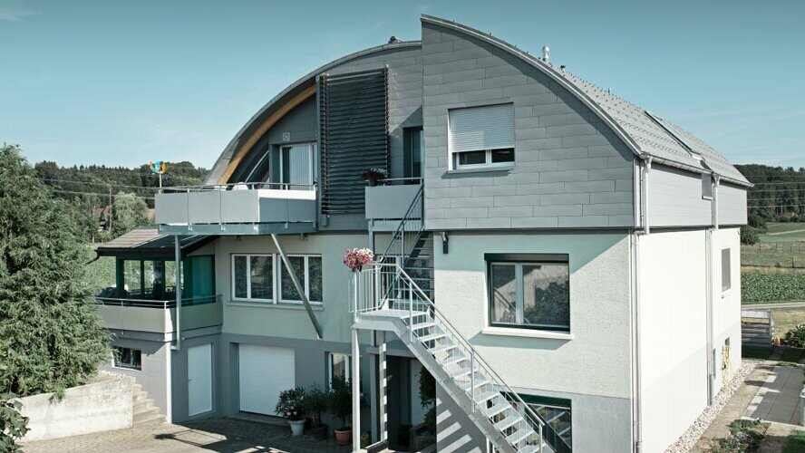 Stambena kuća s bačvastim krovom pokrivenim krovnim pločama PREFA i sustavom Prefalz svijetlosive boje P.10