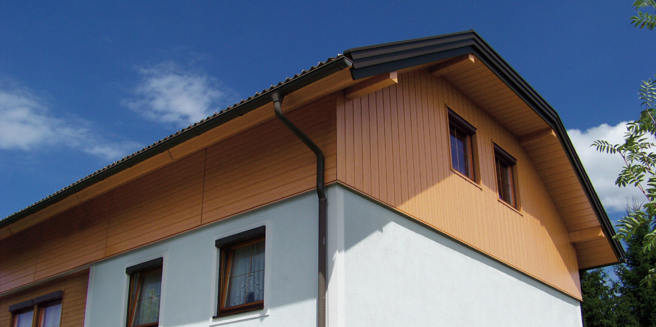 Velika obiteljska kuća s poluskošenim krovom i oblogom zabata s PREFA kazetama Siding u optici prirodni hrast