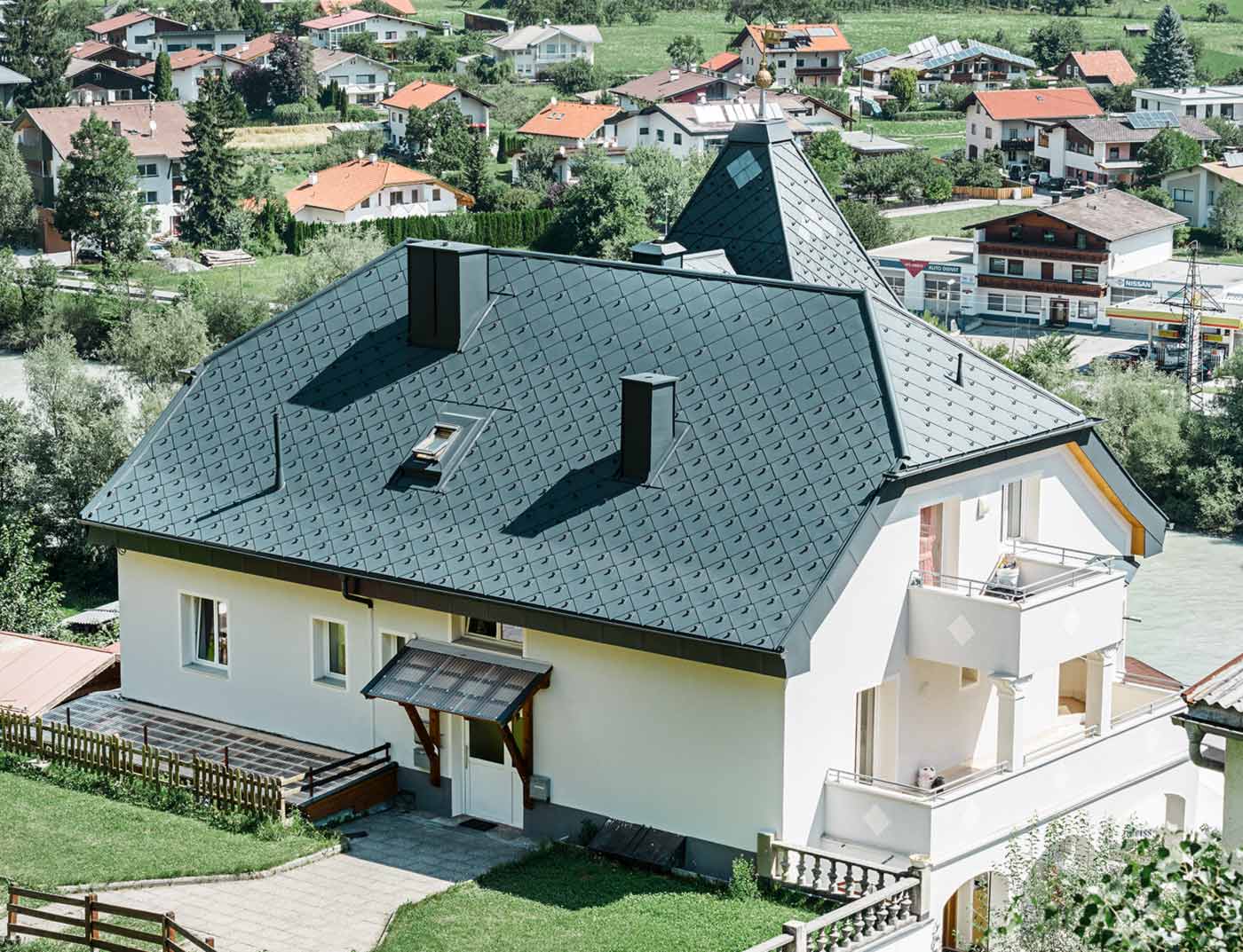 Referentni objekt PREFA krovni romb 44 × 44 antracit Četverostrešni krov sa zasjekom i tornjićem, pokriven aluminijskim krovnim rombom 44 × 44 u antracit boji.
