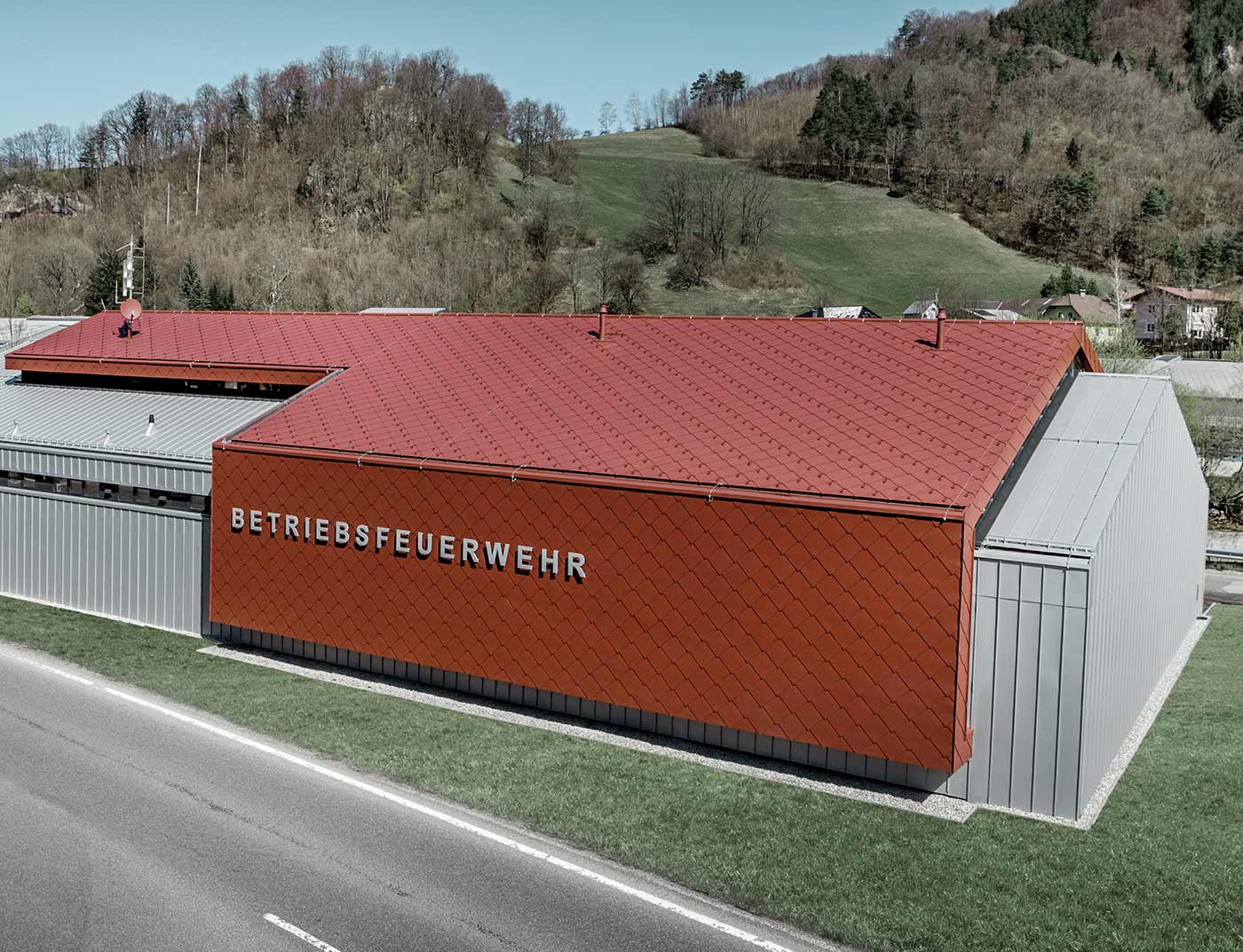 Referentni objekt PREFA krovni romb 44 × 44 oksid crvena Nova zgrada vatrogasne službe tvrtki PREFA i Neuman Aluminium obložena je novim krovnim i zidnim rombom 44 x 44 u P.10 oksid crvenoj te Prefalz-om u srebrnoj metalik boji.